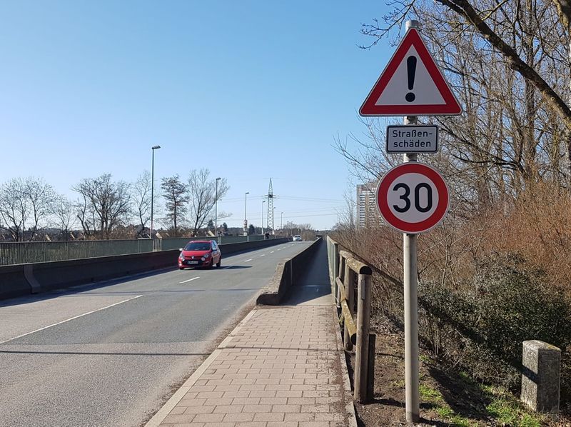 Eine Brück mit Verkehrszeichen und einem Auto. 