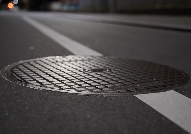 Ein Kanaldeckel auf einer Straße. 