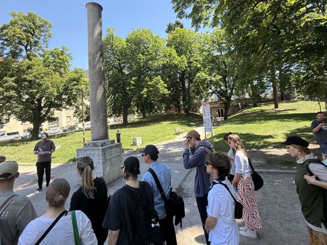 Eine Gedenksäule, die von einer Gruppe Menschen betrachtet wird.