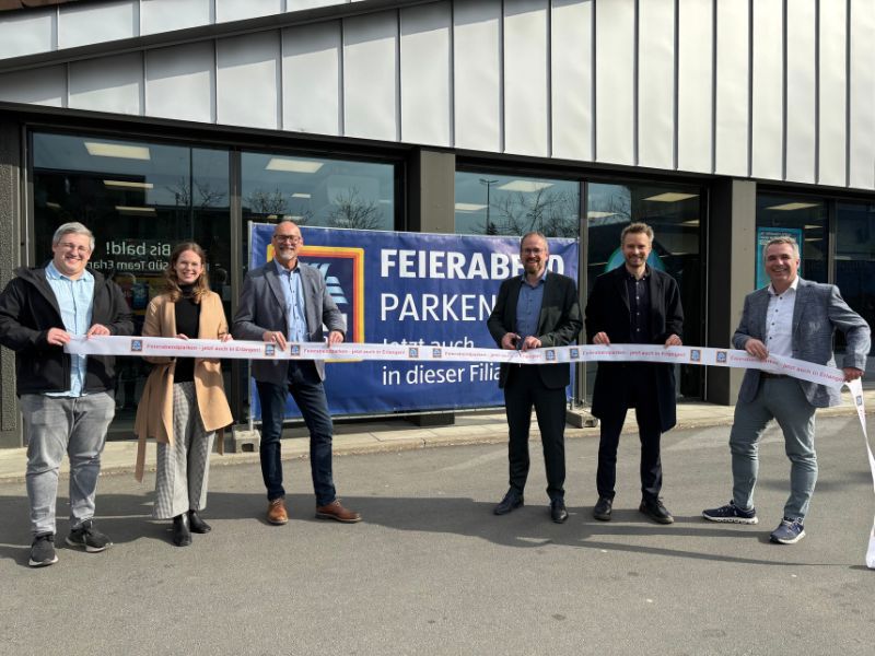 Menschen vor einer Aldi Filiale mit einem Band zum durchschneiden.