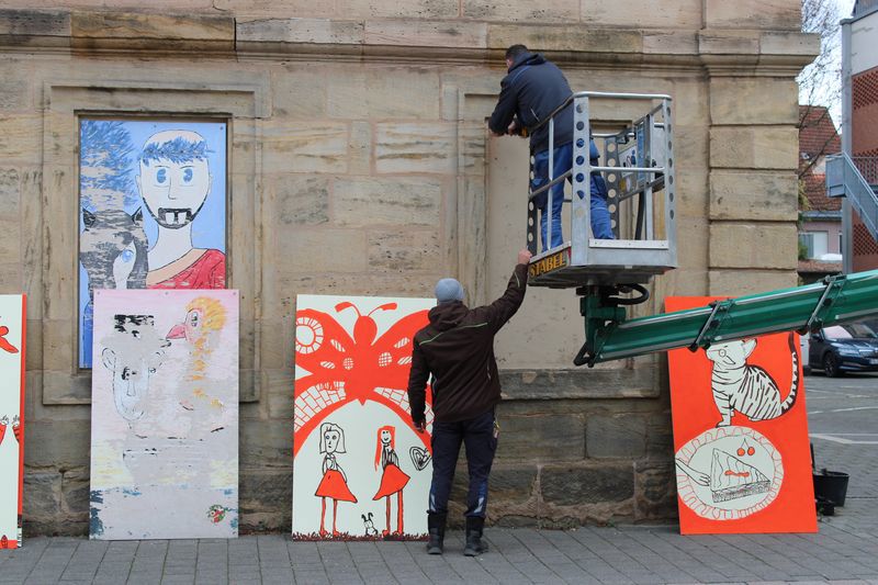 Zwei Männer montieren Fragmente an die Fassade der Jugendkunstschule.