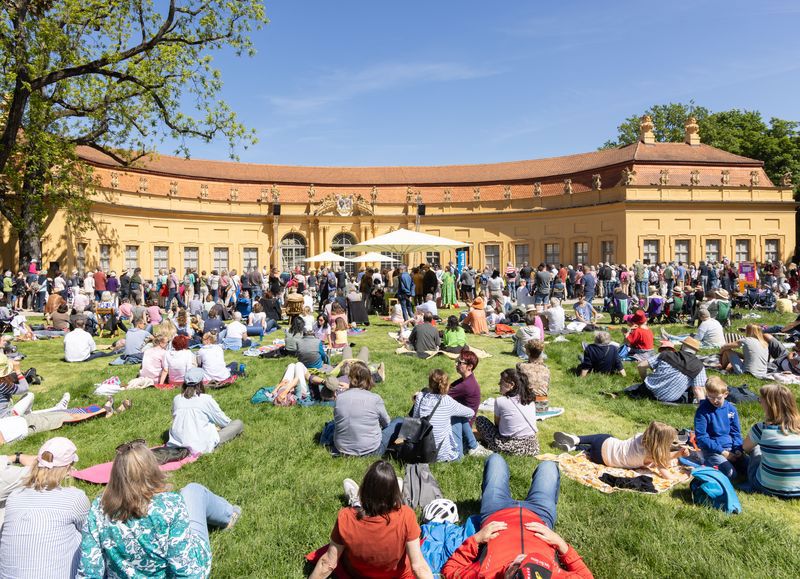 Viele Menschen auf einer Wiese vor dem Schloss.