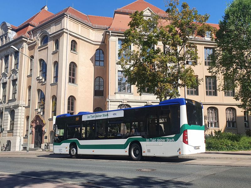 Bus der Erlanger Stadtwerke mit zwei Häuser im Hintergrund und rechts zwei Bäume