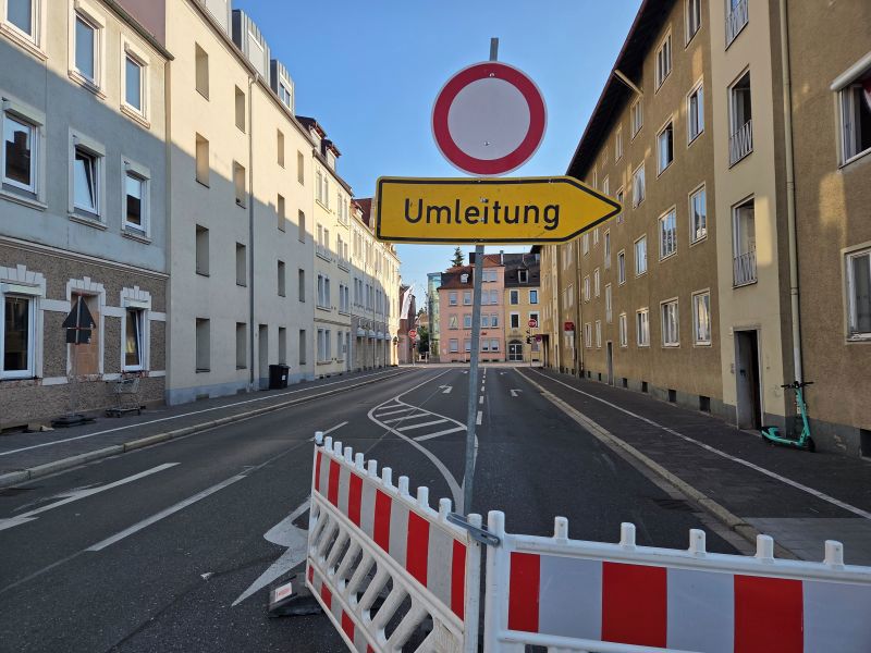 Eine Straße ohne Auto mit einer Absperrung und einem Umleitungsschild. 