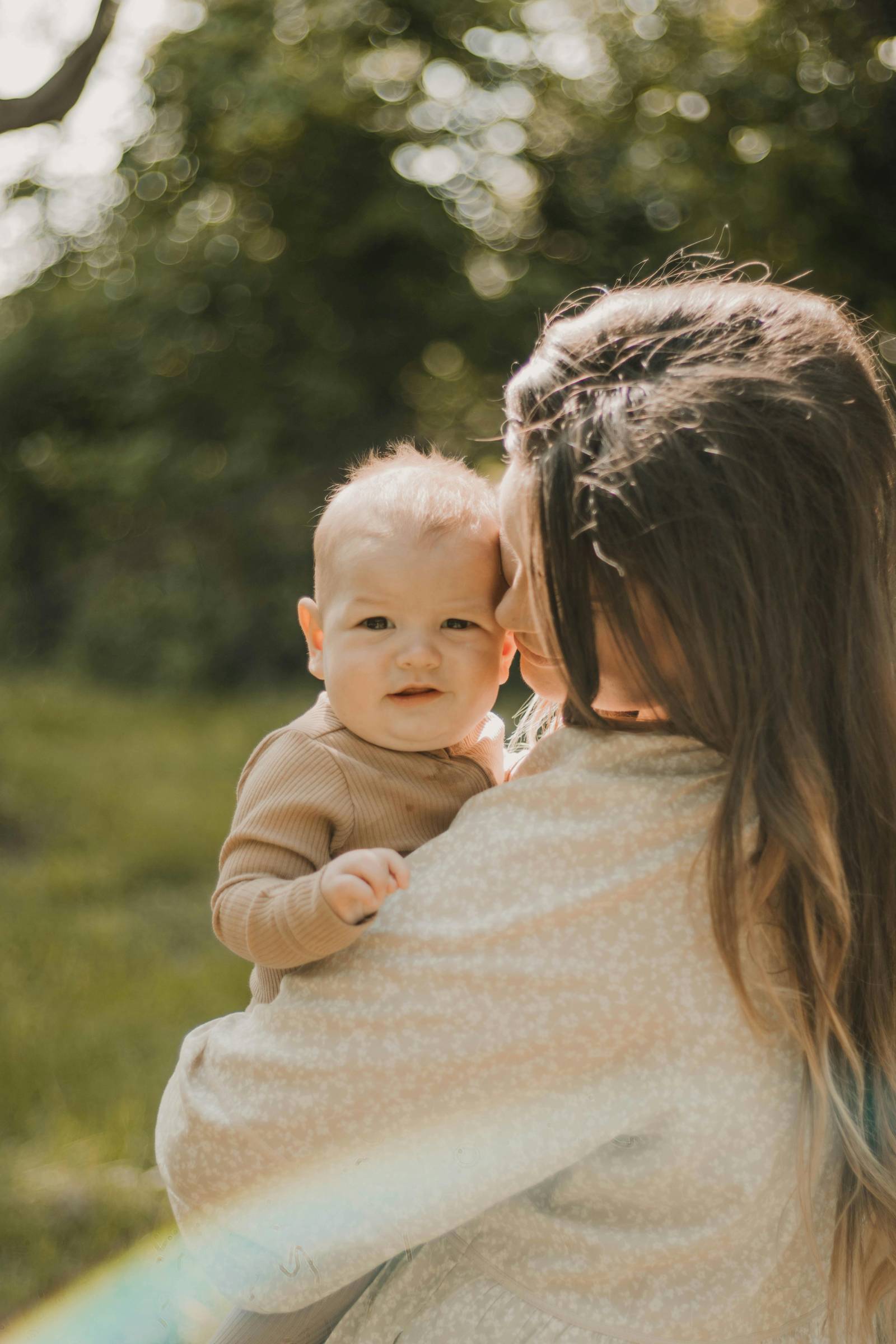 Mutter blickt Baby auf dem Arm liebevoll an.