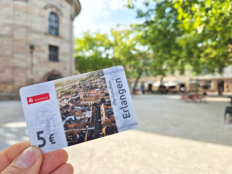 Eine Hand hält einen fünf-Euro-Gutschein in der Hand. 