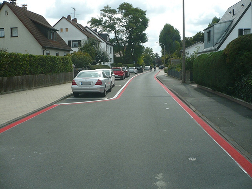 Straße mit parkenden Autos und roten Radfahrer-Schutzstreifen