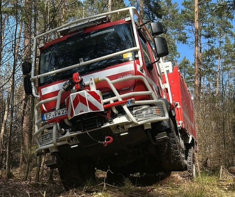 Ein Feuerwehrfahrzeug steht im Wald.