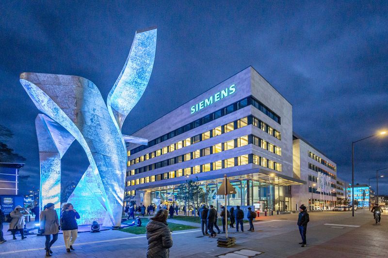 Beleuchtetes Siemens-Gebäude bei Nacht mit Menschen