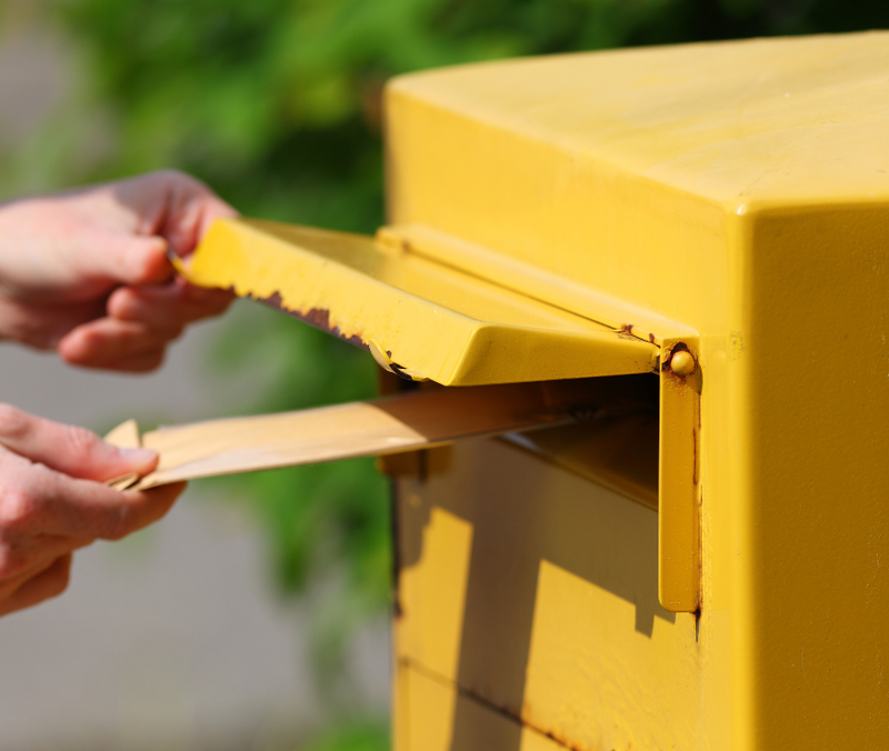 Ein Brief wird in einen Briefkasten geworfen. 