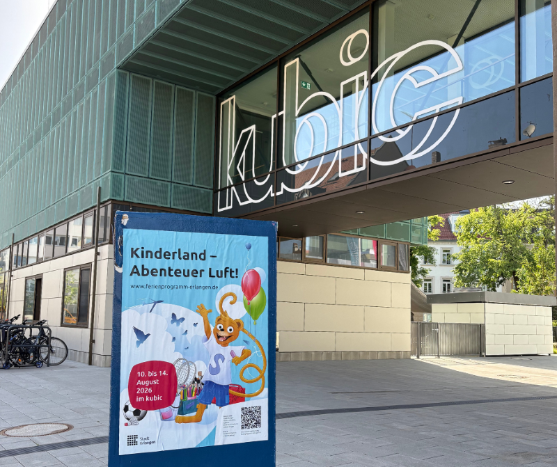 Ein Gebäude mit dem Schriftzug kubic sowie einem Werbeaufsteller zum Kinderland vor dem Gebäude. 