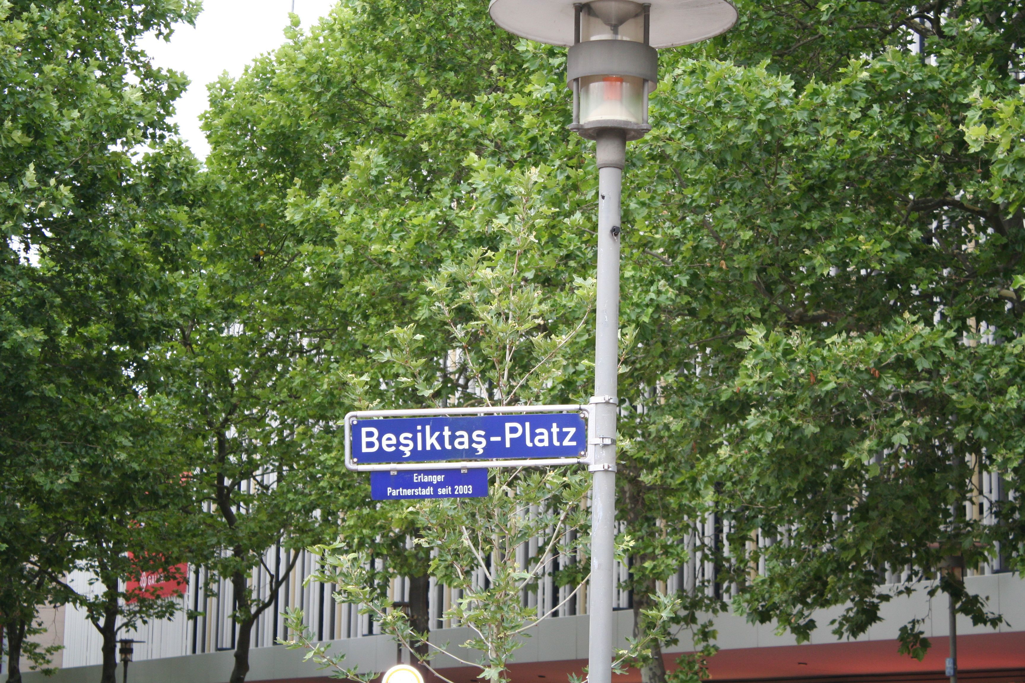 Schild Beşiktaş-Platz, umrahmt von Bäumen mit Gebäude im Hintergrund