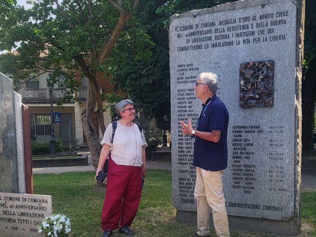 Zwei Menschen sprechen vor einem Denkmal.