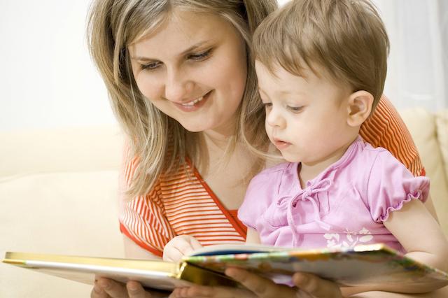 Frau schaut mit Kind Buch an