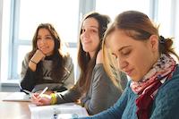 Three young women sitting at the table and learning