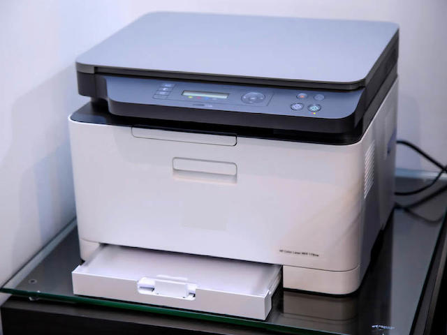 Ein Druckergerät mit Papier steht auf Tisch.