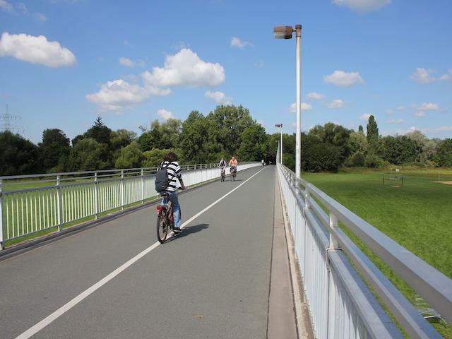 Несколько велосипедистов на мосту.