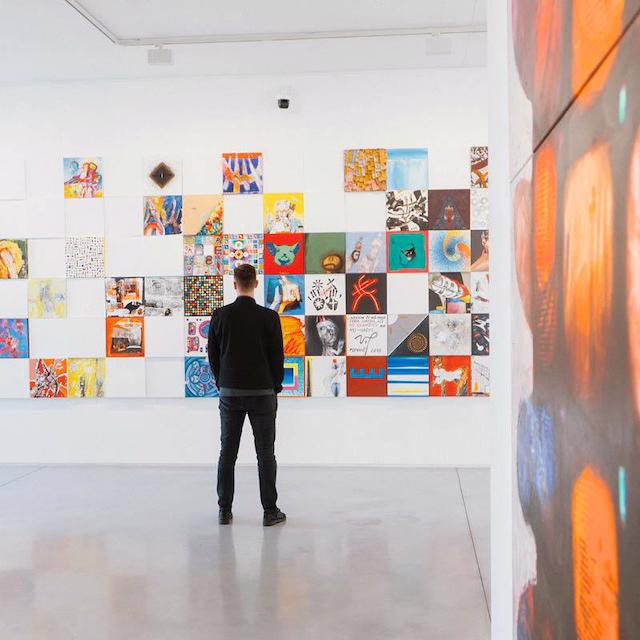 Person standing in front of a picture wall in an art gallery.