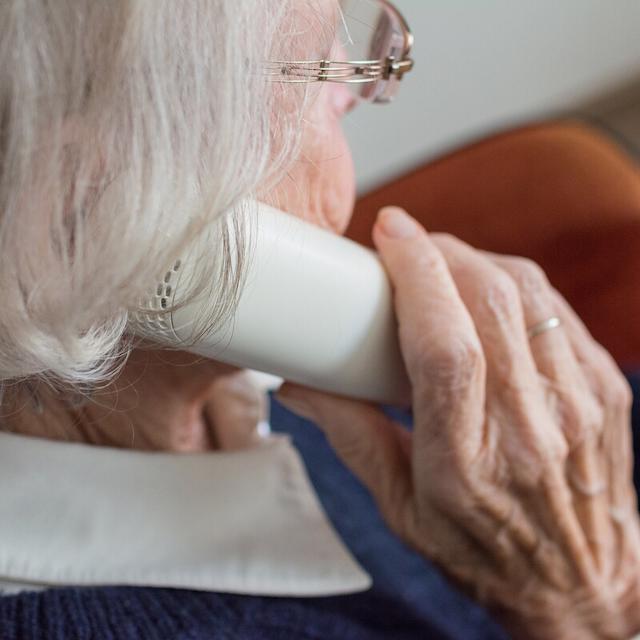 Eine ältere Dame mit dem Telefonhörer in der Hand