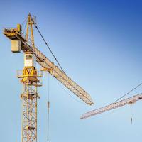 Two yellow cranes in front of a blue sky.